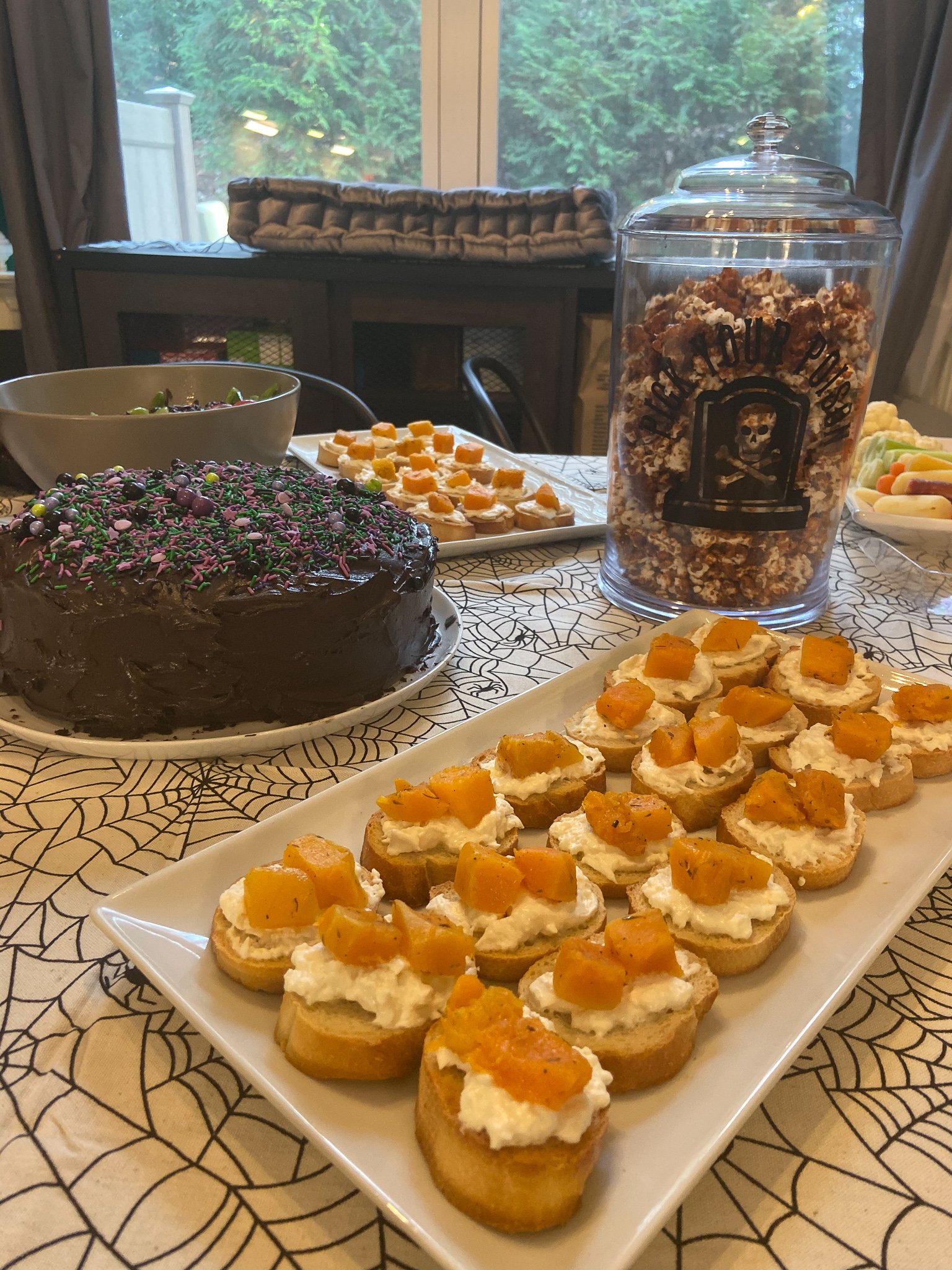This is a table full of Halloween dishes, focused on trays of squash crostini.