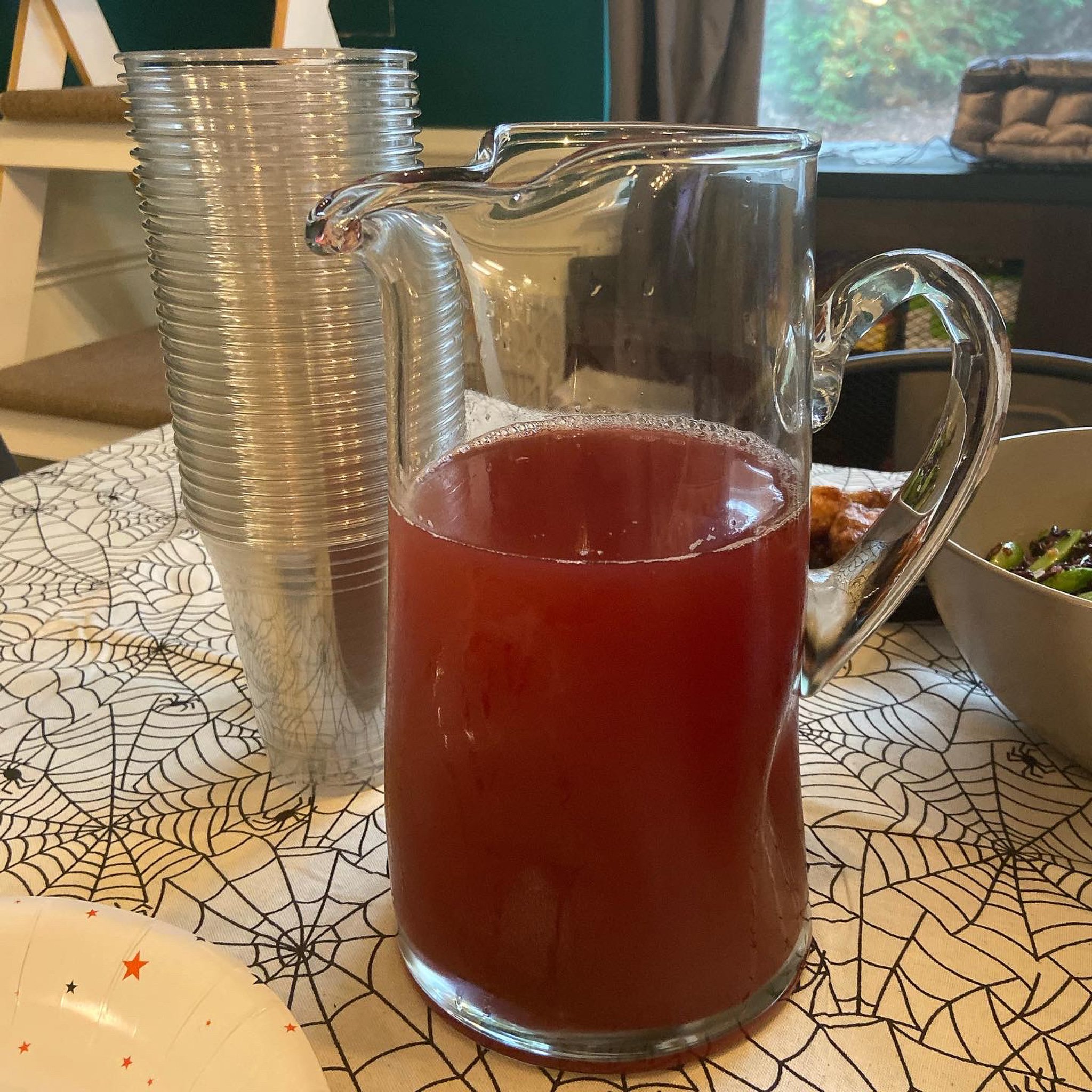 This is a glass pitcher of bright red punch.