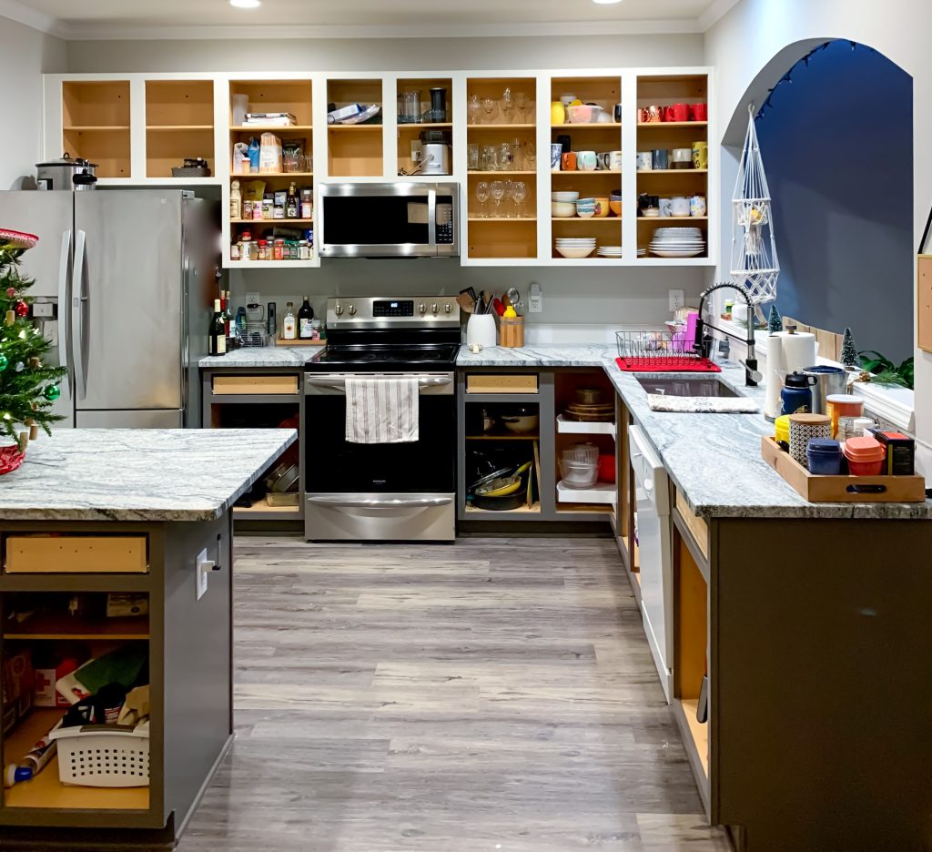 This is a kitchen with no doors on the cabinets, so you can see the dishes and spices inside the cabinet.